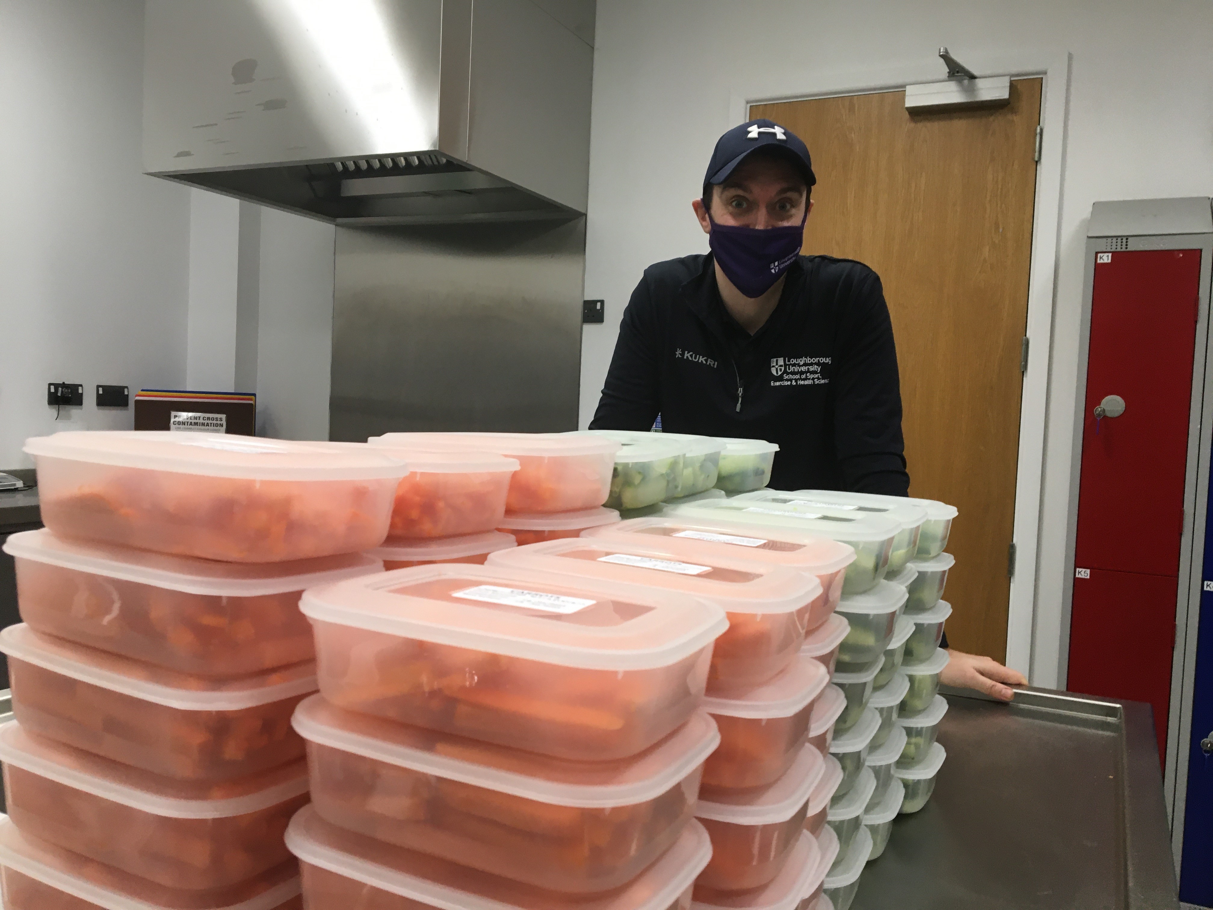 Dr Chris McLeod stands behind stacks of boxes of vegetables prepared for local preschools